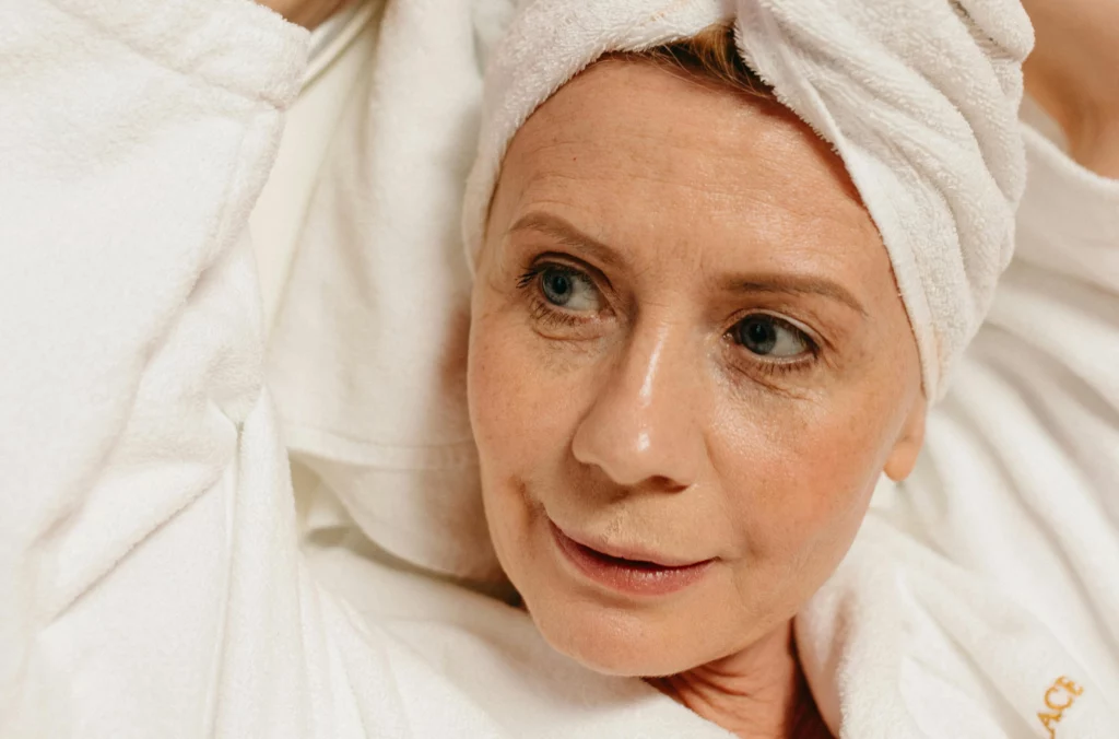 A mature woman in a spa robe with a towel wrapped around her head, showcasing radiant skin. Ideal for brands offering wholesale argan oil for wrinkles in anti-aging skincare products.