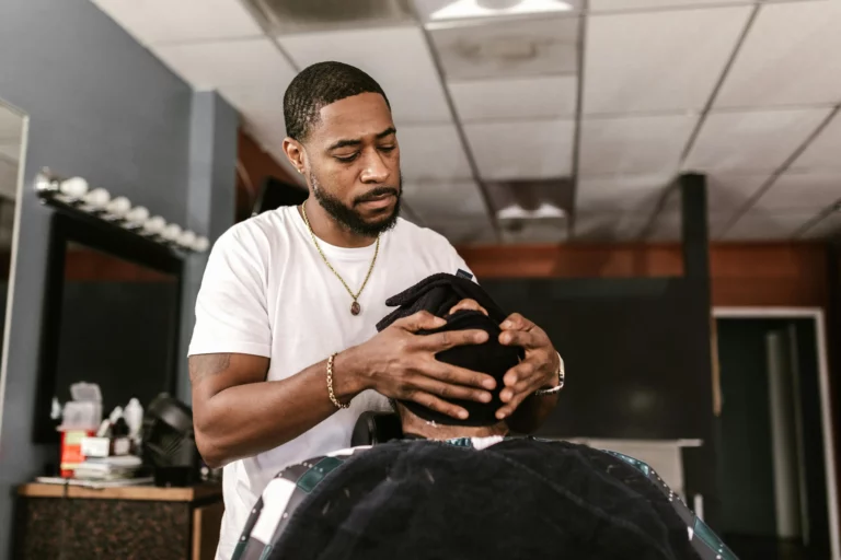 Barber performing a hot towel treatment on a client, demonstrating B2B product applications for wholesale argan oil in premium grooming routines.
